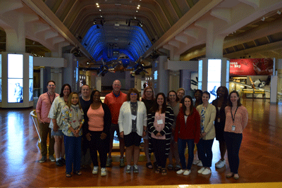Educators posed in front of the Cornerstone in the Museum of American Innovation